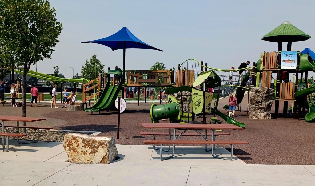 Playground at Discovery Park in Meridian, Idaho, featuring slides, climbing structures, shade canopies, picnic tables, and accessible play areas.