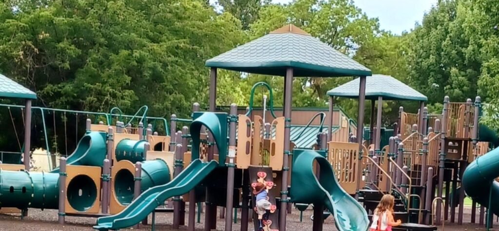 Camel's Back Park Boise, Idaho Children playing on a playground with green slides and tubes. There are tan railings.