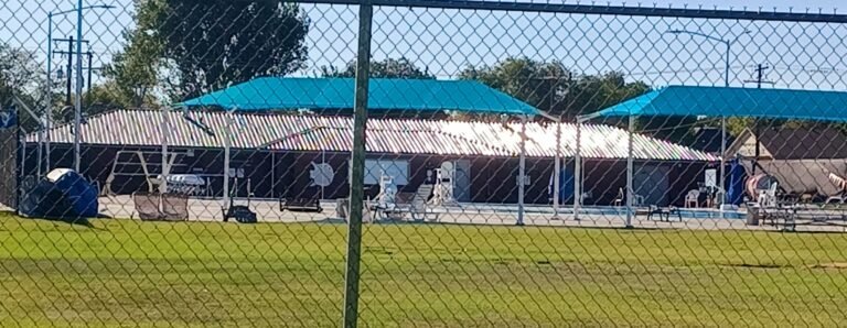 Mountain Home City Pool and shade canopies viewed through the fence